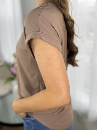 Person wearing a brown t-shirt with a blurred background