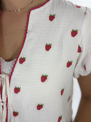 White top with red strawberry patterns on a plain background