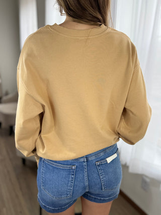 Person wearing a beige sweatshirt and blue shorts in an indoor setting
