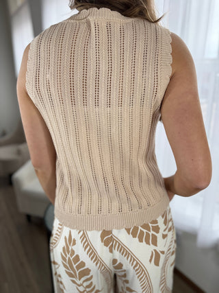 Beige knitted vest worn by a person with a blurred background