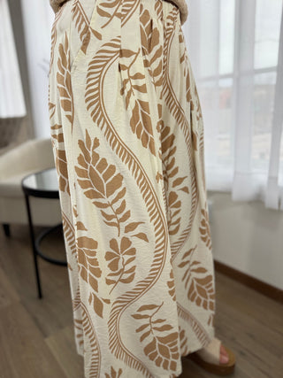 Long beige patterned skirt with a blurred indoor background