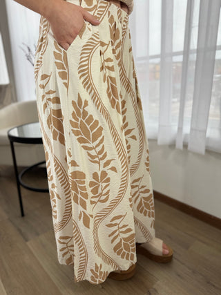 Person wearing a long, patterned dress with a neutral background