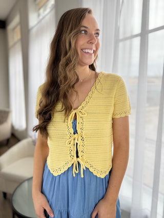 Woman wearing a yellow crochet top in a bright room