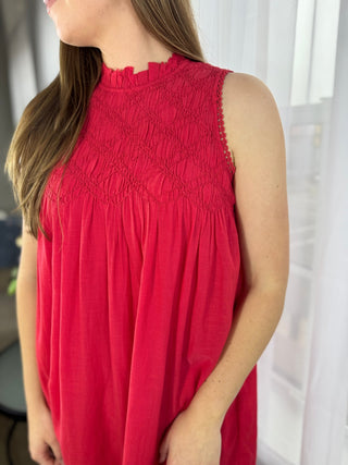 Red sleeveless top worn by a person with a blurred background