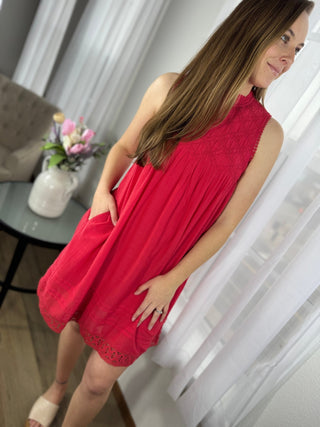 Woman in a red dress standing indoors with a blurred background