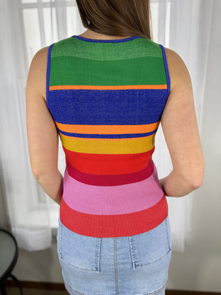 Person wearing a colorful striped tank top with a white curtain background