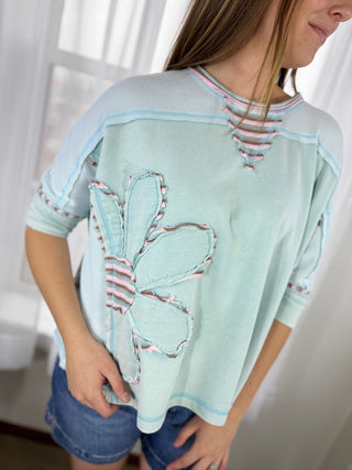 Light blue sweater with butterfly design worn by a person indoors.