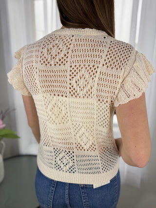 Woman wearing a beige crochet top with a white background