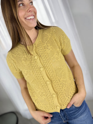 Woman wearing a yellow knitted cardigan against a white background