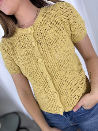 Person wearing a yellow knitted cardigan with a white background