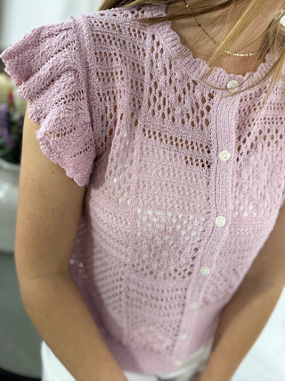 Close-up of a pink knitted top with ruffled sleeves.