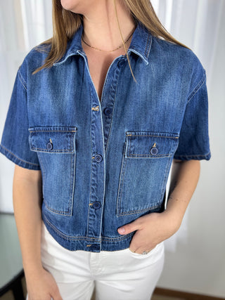 Person wearing a blue denim jacket with a plain background