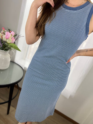 Woman wearing a blue and white striped dress in a room with a table and flowers.