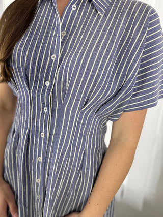 Close-up of a person wearing a blue and white striped dress with a blurred background