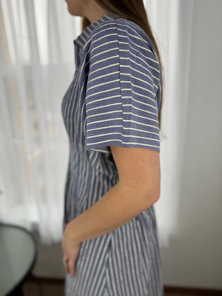 Person wearing a blue and white striped dress with a blurred background