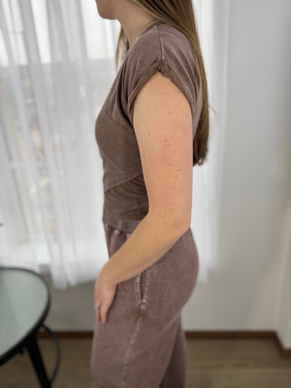 Woman wearing a brown dress standing in a room with white curtains.