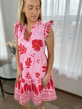 Woman wearing a pink dress with red floral patterns indoors.