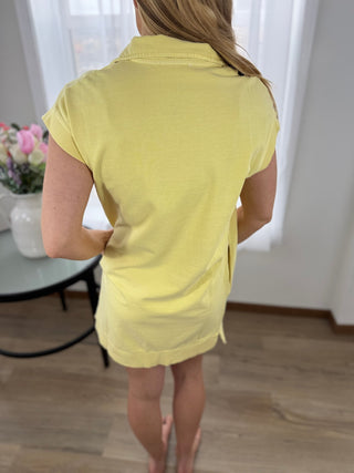 Person wearing a yellow dress standing indoors with a blurred background