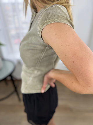 Person wearing a beige top and black pants in an indoor setting