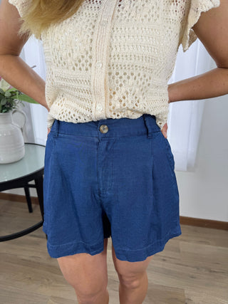 Person wearing a white crochet top and blue shorts in an indoor setting