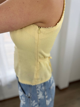 Person wearing a yellow top and blue floral pants with a blurred background
