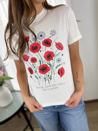 Person wearing a white t-shirt with red floral design and text.