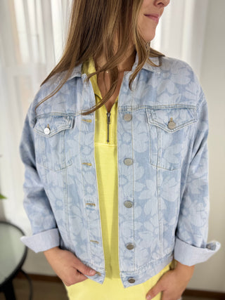 Person wearing a light blue denim jacket over a yellow top indoors.