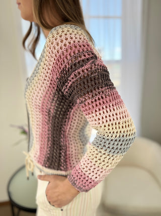 Person wearing a colorful crocheted sweater in a blurred indoor setting