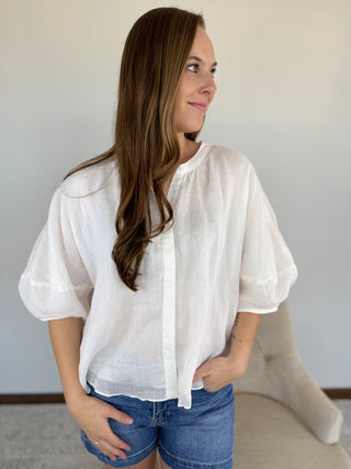 Woman wearing a white blouse and blue shorts against a plain background