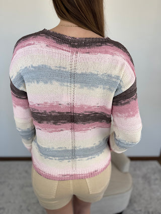 Person wearing a colorful striped sweater with a neutral background