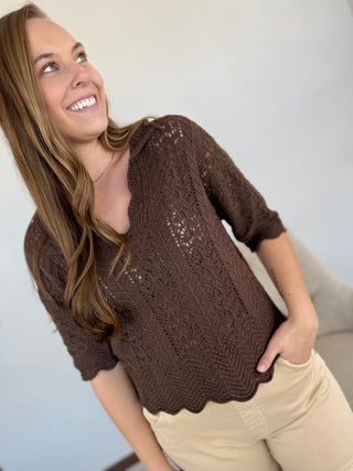 Woman wearing a brown crochet top against a plain background