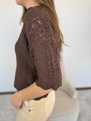 Brown knitted top worn by a person against a white background