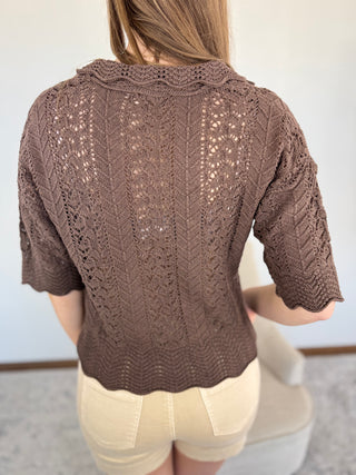 Brown knitted cardigan worn by a person with a plain background