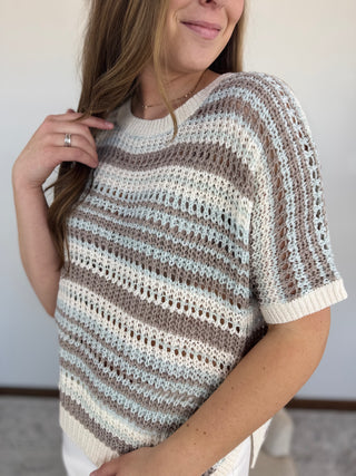 Woman wearing a striped sweater against a neutral background