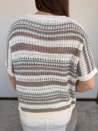 Person wearing a striped sweater with a neutral background