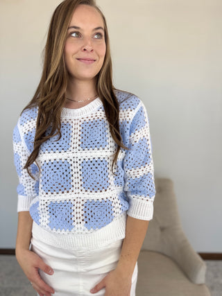 Woman wearing a blue and white patterned sweater against a neutral background