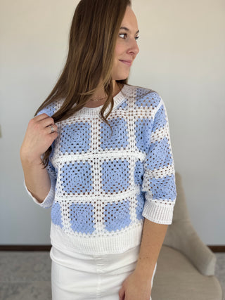 Woman wearing a blue and white checkered sweater against a plain background