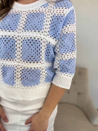 Person wearing a blue and white patterned sweater with a blurred background