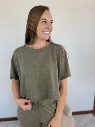Woman wearing an olive green outfit against a plain background
