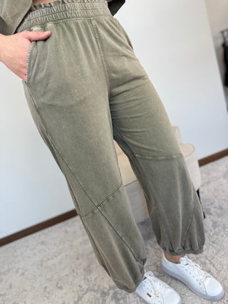 Person wearing olive green pants with a white background