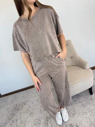 Person wearing a brown outfit with white sneakers in a room with a gray chair.