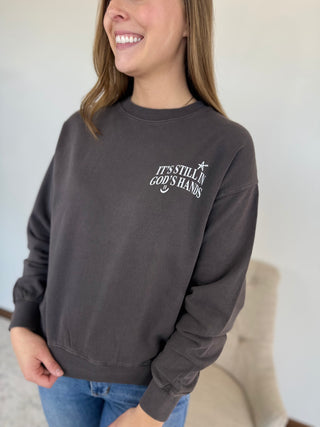 Person wearing a dark gray sweatshirt with text, standing indoors.