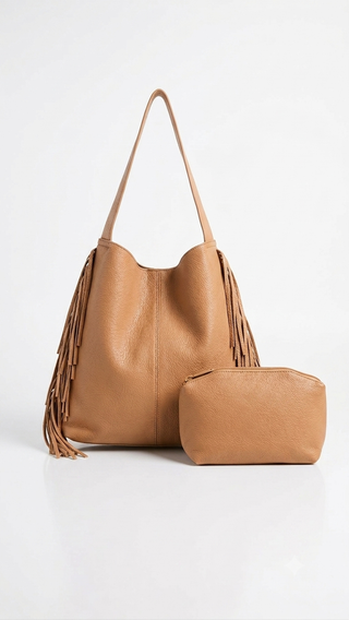 A tan leather hobo shoulder bag with long fringe detailing on the sides, shown alongside a matching small zippered pouch on a clean white background.