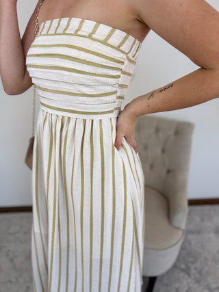 Woman wearing a white dress with gold stripes in an indoor setting.