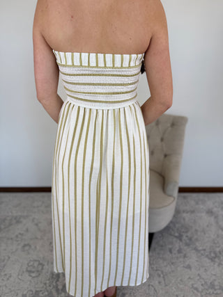 Person wearing a strapless dress with green and white vertical stripes in a room.