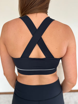 Navy sports bra with criss-cross back design on a neutral background