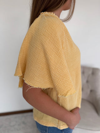 Person wearing a yellow textured top with a blurred background