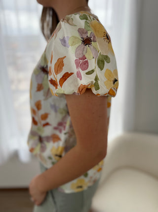 Person wearing a floral blouse with a blurred background