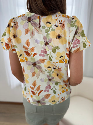 Person wearing a floral-patterned shirt with a neutral background