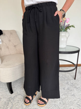 Lady standing wearing a black drawstring pant.